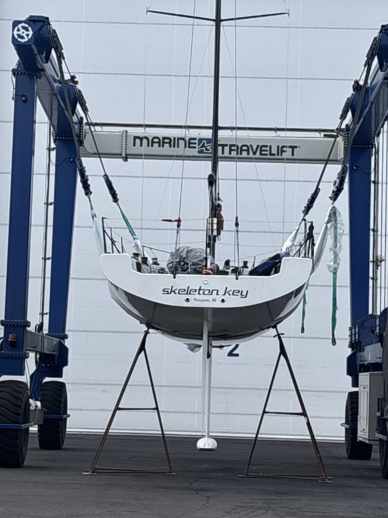 Sailboat suspended from a marine travel lift at the yard